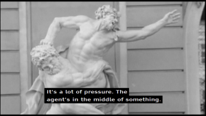 Screenshot from a television documentary of a white sculpture with two intertwined male figures. A machine-translated  subtitle at the bottom of the screen says: “It’s a lot of pressure. The agent’s in the middle of something."